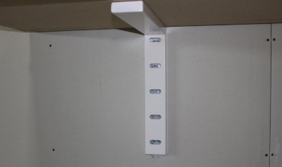 A white heavy–duty hybrid bracket underneath a wall mounted tabletop closeup shot